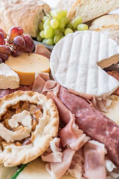 Charcuterie Board,This meat and cheese board is filled with so many delicious items and it’s not just limited to meat and cheese! Fruit, mini pies and even some bread go perfectly with this delicious tray of goodies! #atablefullofjoy #cheese #charcuterie #bread #yummy