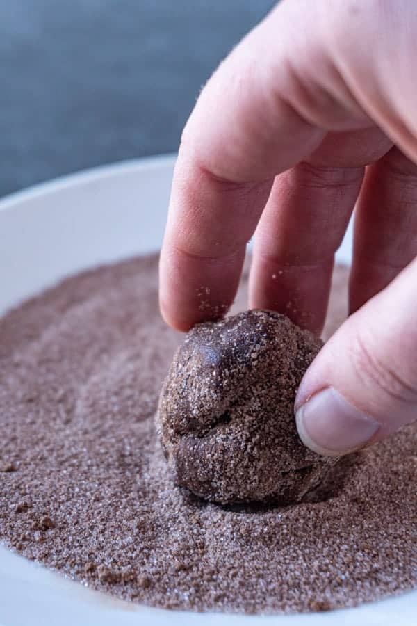 Cookie dough being rolled in sugar cocoa coating